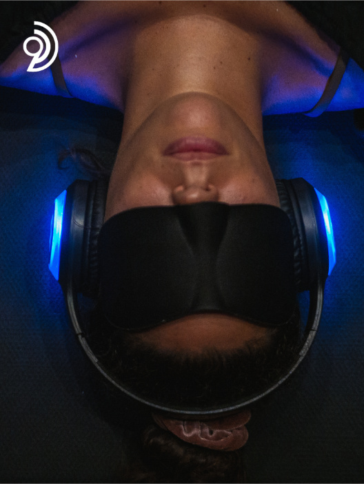 9D Breathwork Session image, from Breathwork Coach in Barrie, where a woman is laying down with her eyes covered and a headset on and on from the shoulders up is shown