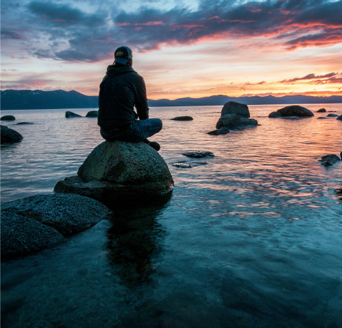 HeartMath Services Image, for Mental Health First Responders Barrie, of man sitting on rocks looking out into the water at sunset